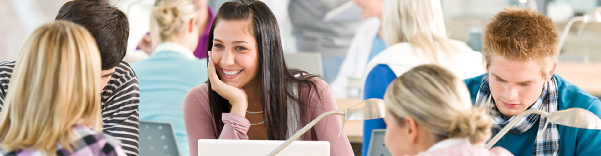 Smiling woman working on a laptop in a bright office.