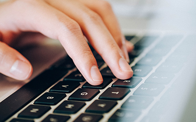 Close-up of fingers typing on a laptop keyboard.