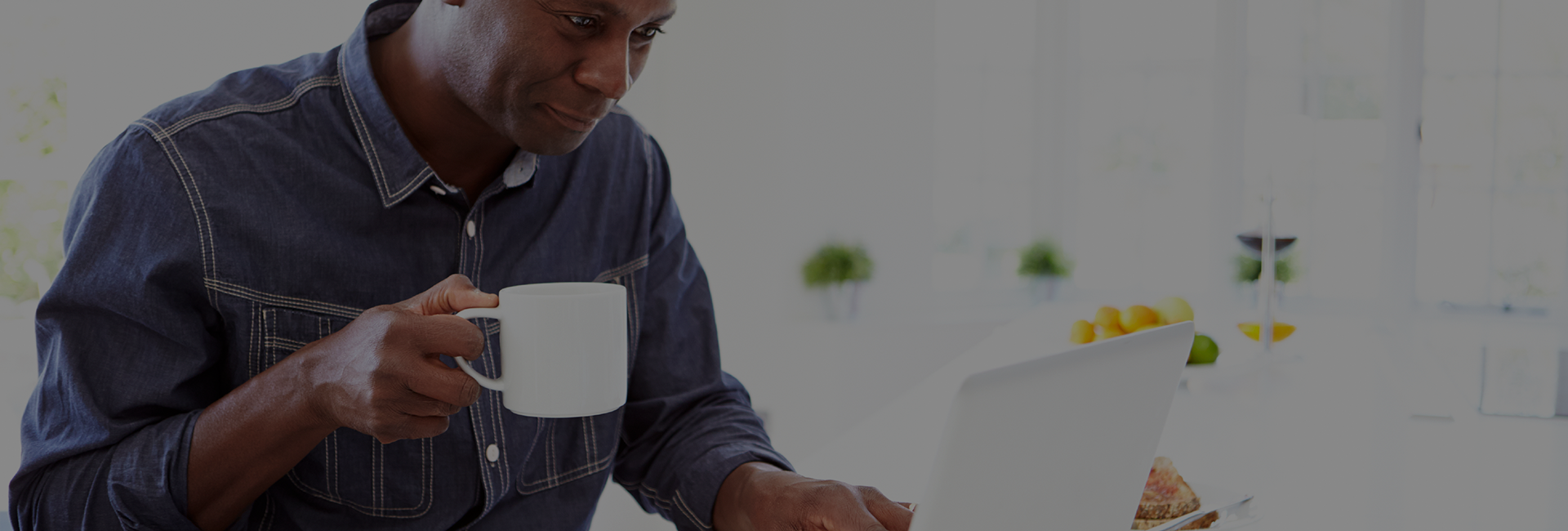 Man drinking coffee while using a laptop.