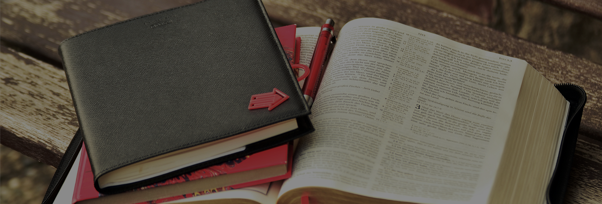 Open book with notebooks and pens nearby.